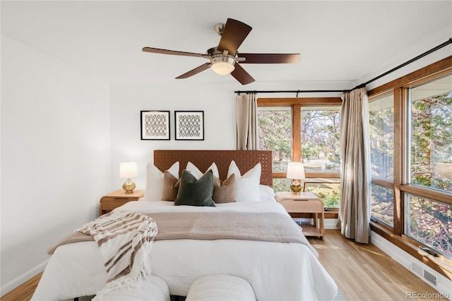 bedroom featuring ceiling fan, visible vents, baseboards, and light wood-style flooring