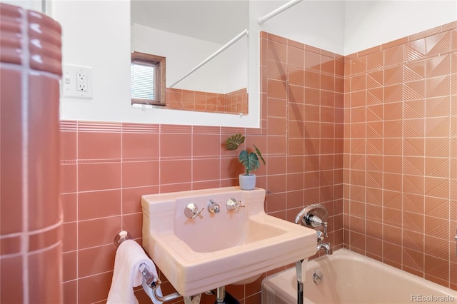 bathroom with tile walls, tub / shower combination, and a sink