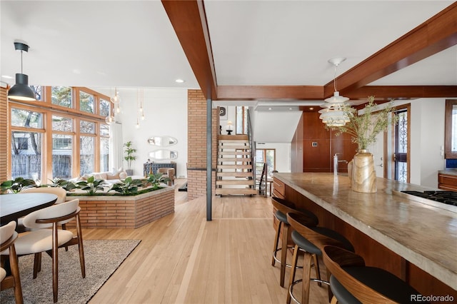 dining area with stairway, beam ceiling, light wood-style floors, and an inviting chandelier