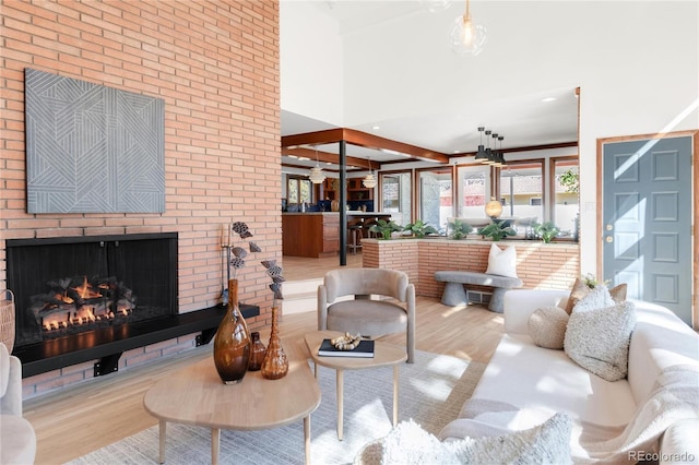 living room featuring a towering ceiling, brick wall, wood finished floors, and a fireplace