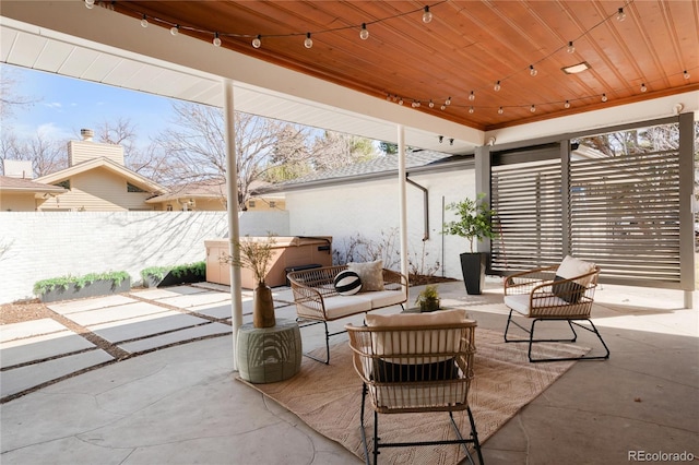 view of patio / terrace with an outdoor living space, fence, and a hot tub