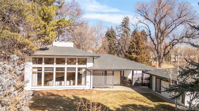 back of house featuring a carport and roof with shingles