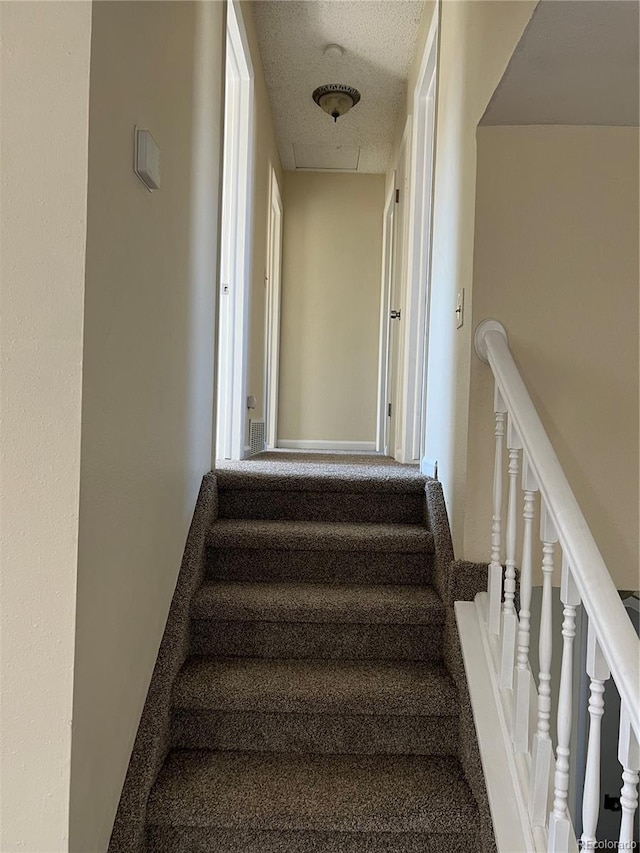 staircase with a textured ceiling