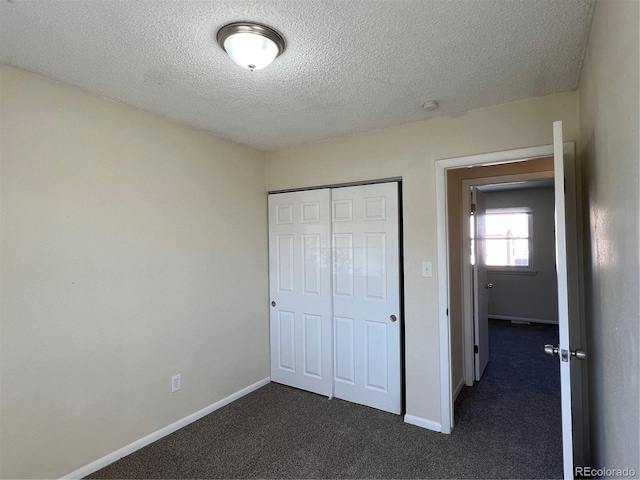 unfurnished bedroom featuring dark colored carpet, a textured ceiling, and a closet