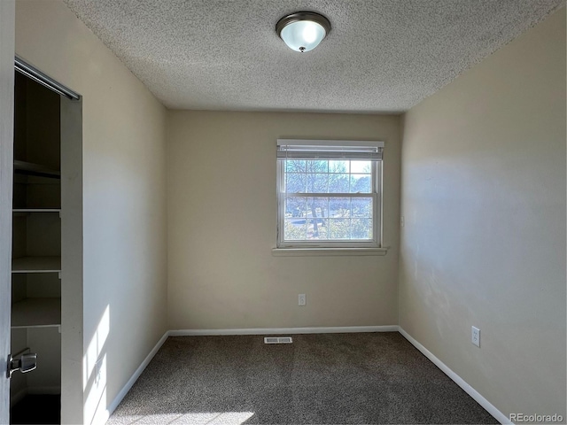 carpeted empty room featuring a textured ceiling