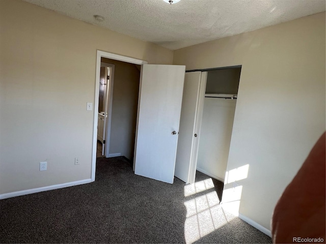 unfurnished bedroom with dark colored carpet, a textured ceiling, and a closet