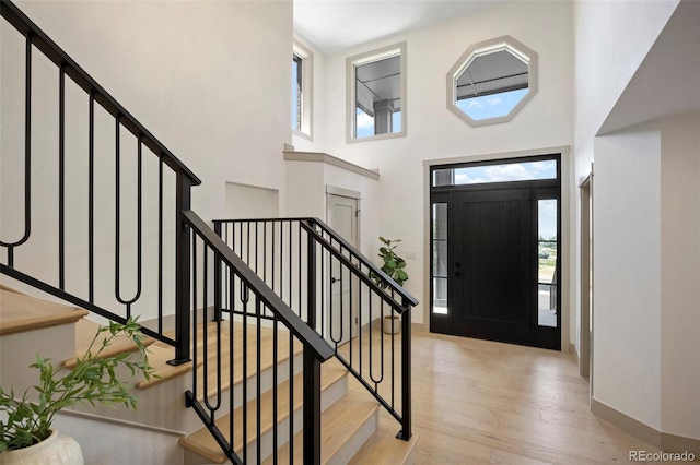 entrance foyer with light hardwood / wood-style flooring and a towering ceiling