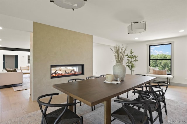 dining room featuring a multi sided fireplace and light wood-type flooring