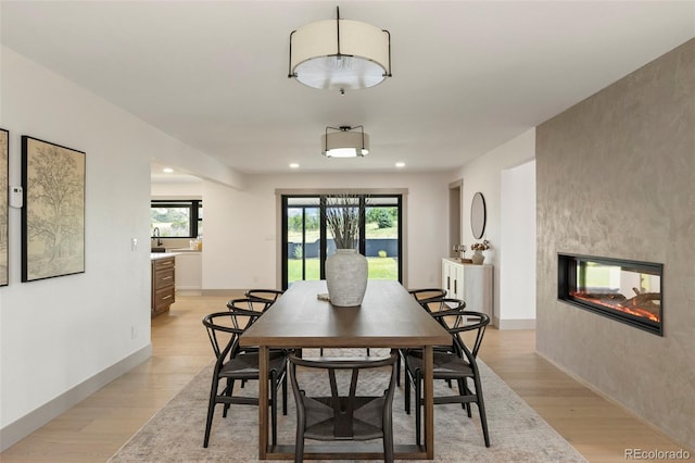 dining space featuring a large fireplace and light wood-type flooring