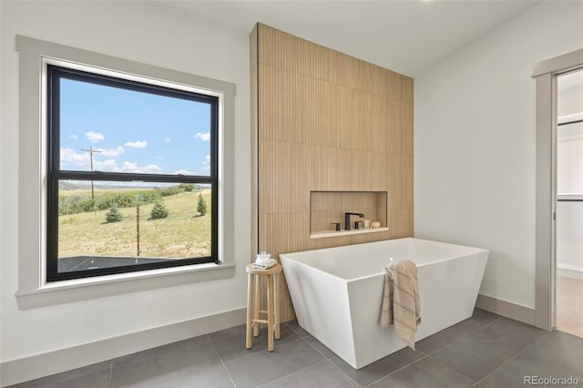 bathroom with tile patterned floors, a bath, and a wealth of natural light