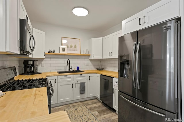 kitchen featuring black appliances, sink, butcher block countertops, backsplash, and white cabinetry