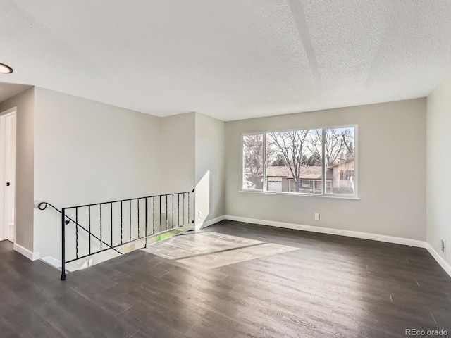 unfurnished room with baseboards, a textured ceiling, and wood finished floors