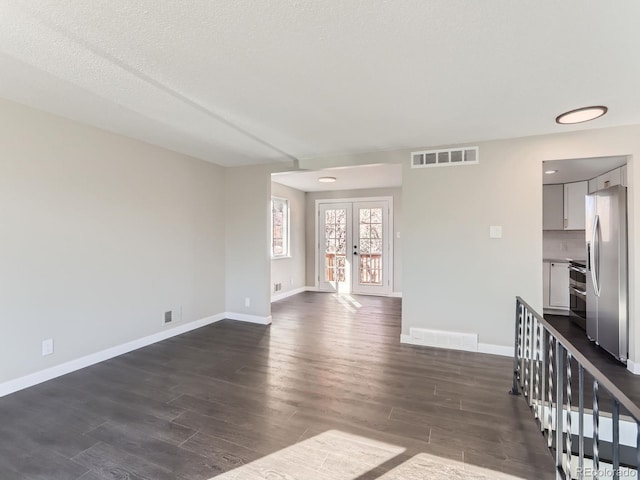 spare room featuring visible vents, baseboards, dark wood-style flooring, and french doors