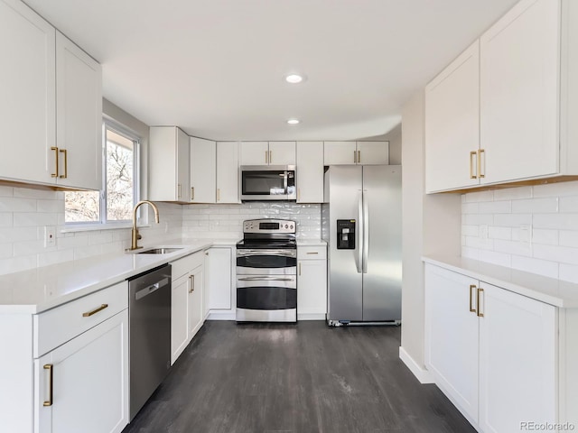 kitchen with dark wood-style flooring, a sink, light countertops, appliances with stainless steel finishes, and backsplash