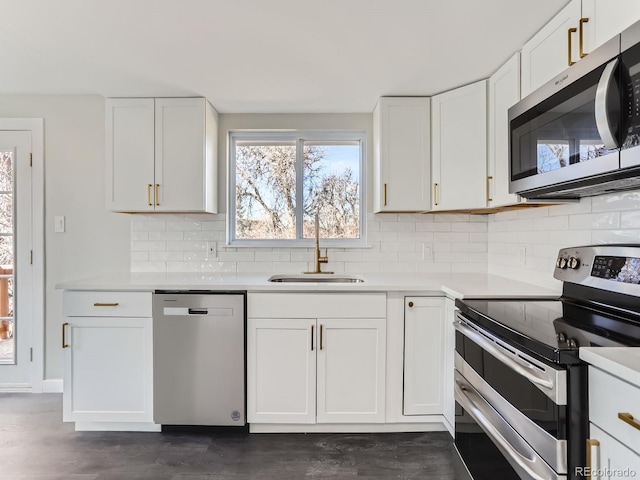 kitchen featuring a sink, backsplash, white cabinetry, stainless steel appliances, and light countertops