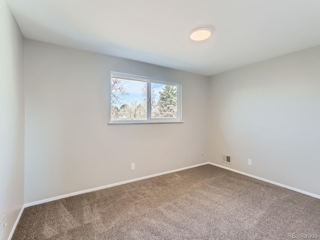 unfurnished room featuring visible vents, baseboards, and dark colored carpet