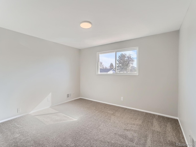 carpeted spare room featuring baseboards and visible vents