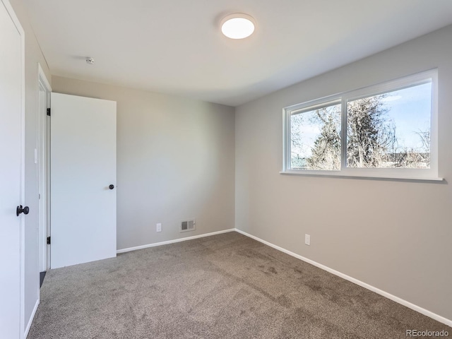 empty room with carpet flooring, baseboards, and visible vents