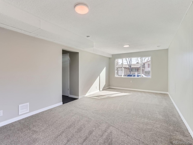 spare room with visible vents, carpet floors, a textured ceiling, and baseboards