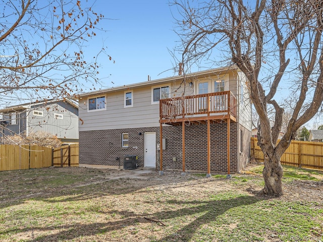 rear view of property with a fenced backyard, brick siding, and a wooden deck