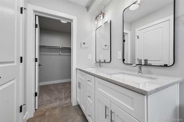 bathroom featuring double vanity, tile patterned flooring, a spacious closet, and baseboards