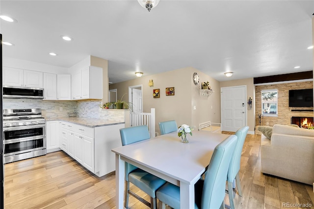 3561 W 131st Ave, Broomfield, CO 80020 - dining room featuring light wood-style floors, recessed lighting, a fireplace, and baseboards