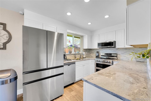 3561 W 131st Ave, Broomfield, CO 80020 - kitchen featuring stainless steel appliances, a sink, white cabinets, light wood-type flooring, and light stone countertops