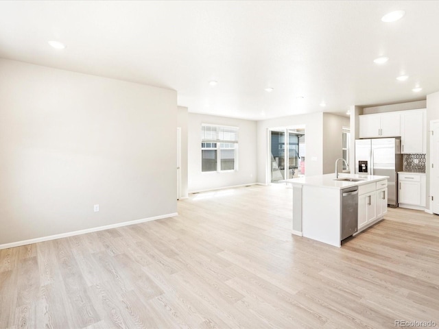 kitchen with decorative backsplash, light wood-style flooring, appliances with stainless steel finishes, open floor plan, and a sink