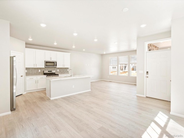 kitchen with light wood-style flooring, stainless steel appliances, a sink, light countertops, and decorative backsplash