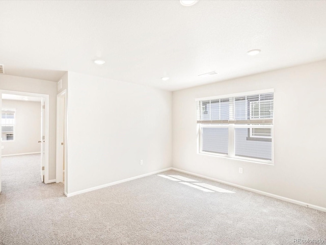 carpeted spare room with visible vents and baseboards