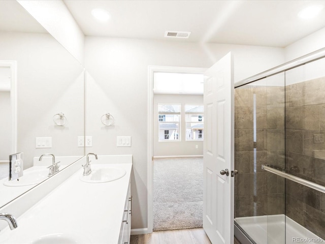 full bath with double vanity, a shower stall, visible vents, and a sink