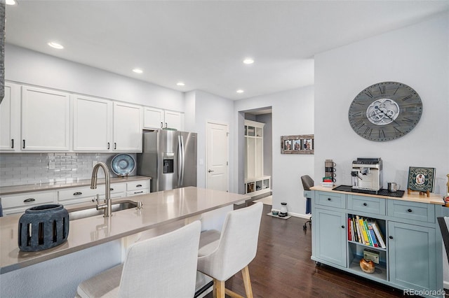 kitchen with dark wood-style floors, stainless steel refrigerator with ice dispenser, a kitchen bar, and white cabinetry