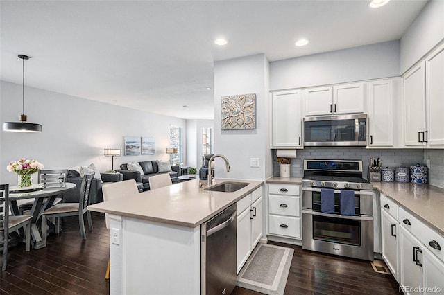 kitchen with open floor plan, hanging light fixtures, a peninsula, stainless steel appliances, and a sink