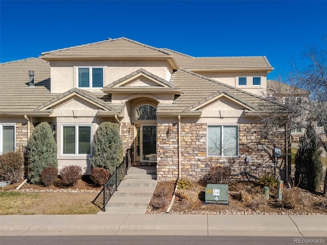 view of front facade with stone siding, stucco siding, and a tiled roof