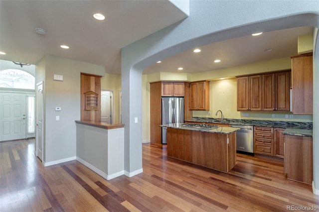 kitchen with baseboards, appliances with stainless steel finishes, wood finished floors, and a center island