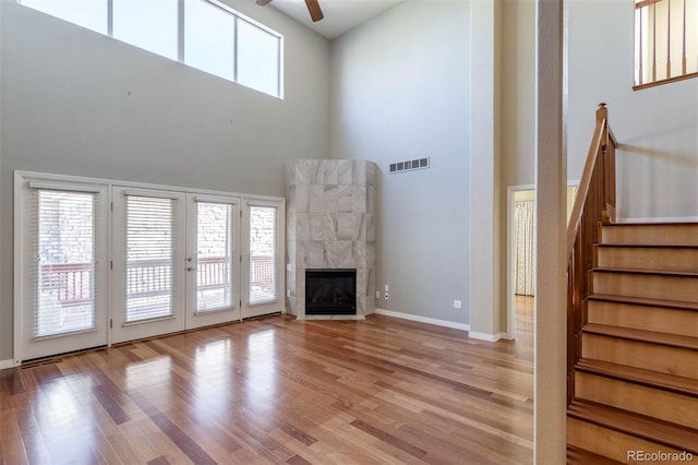 unfurnished living room featuring a wealth of natural light, visible vents, wood finished floors, and a ceiling fan