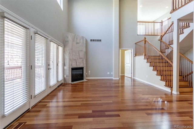 unfurnished living room with visible vents, baseboards, wood finished floors, and stairs