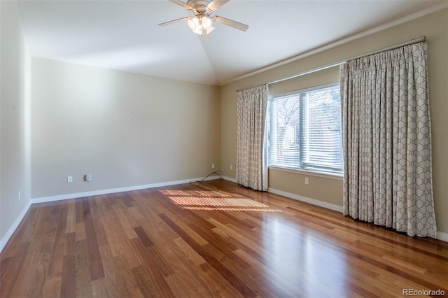 spare room featuring vaulted ceiling, wood finished floors, baseboards, and ceiling fan