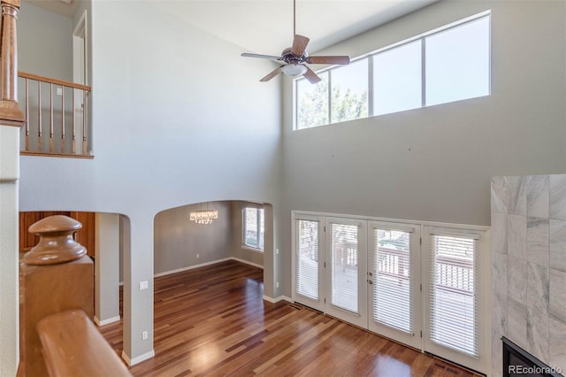 foyer featuring baseboards, french doors, wood finished floors, arched walkways, and a ceiling fan