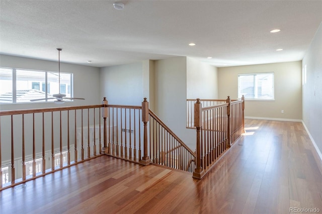 hallway featuring an upstairs landing, recessed lighting, baseboards, and wood finished floors