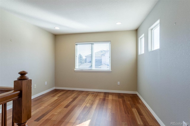 unfurnished room featuring plenty of natural light, wood finished floors, and baseboards