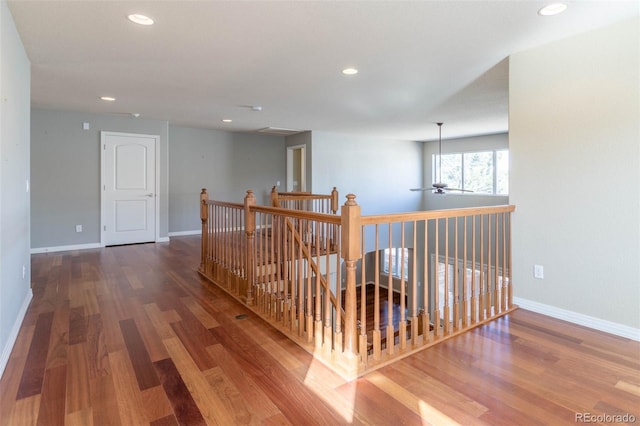 corridor with an upstairs landing, recessed lighting, baseboards, and wood finished floors