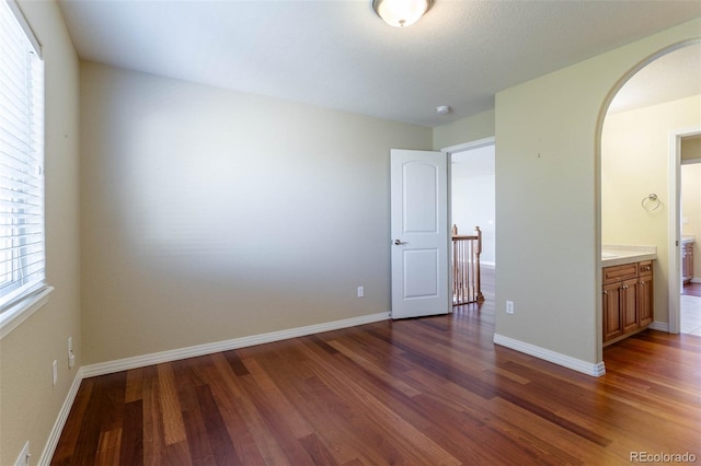 spare room with visible vents, baseboards, arched walkways, and dark wood-style flooring