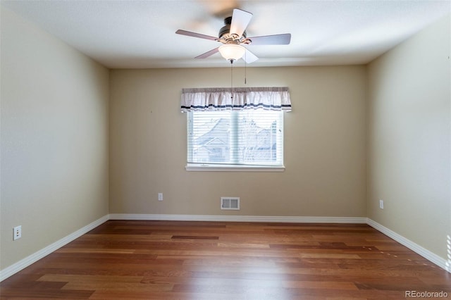 empty room featuring ceiling fan, visible vents, baseboards, and wood finished floors