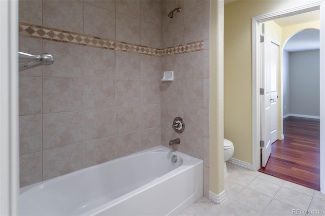 bathroom with tile patterned floors, baseboards, toilet, and bathtub / shower combination