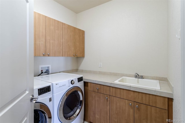 clothes washing area featuring washing machine and clothes dryer, cabinet space, and a sink