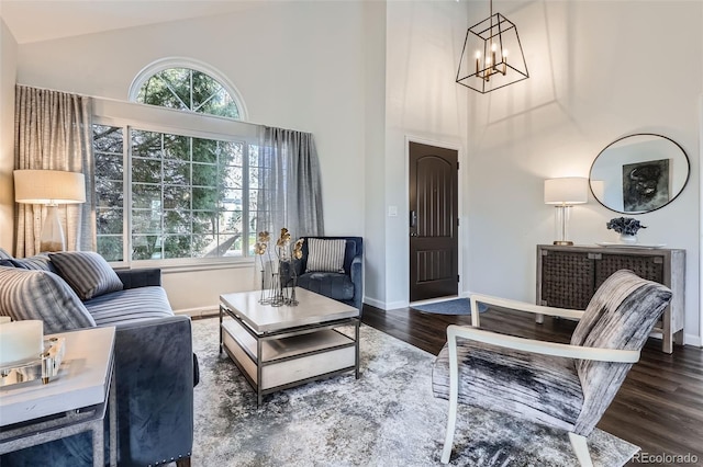 living area with a wealth of natural light, a notable chandelier, baseboards, and wood finished floors