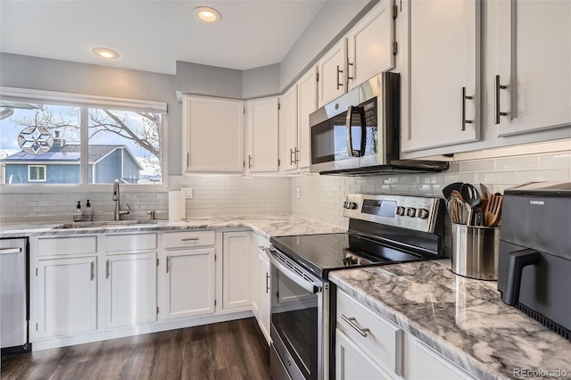 kitchen featuring a sink, dark wood-type flooring, white cabinetry, light stone countertops, and appliances with stainless steel finishes