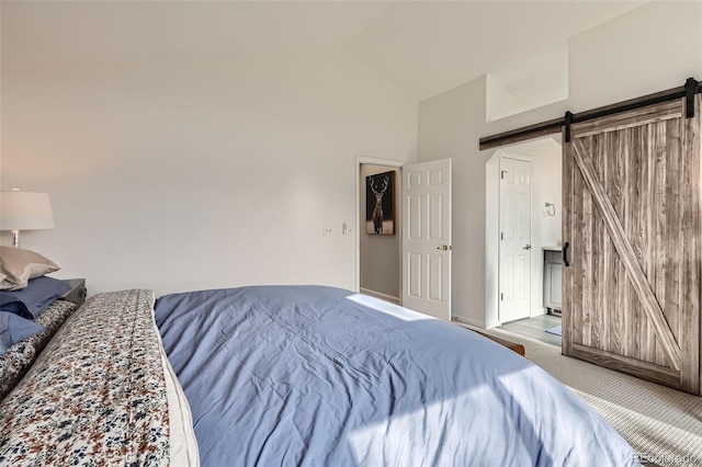 bedroom featuring high vaulted ceiling, a barn door, and carpet floors