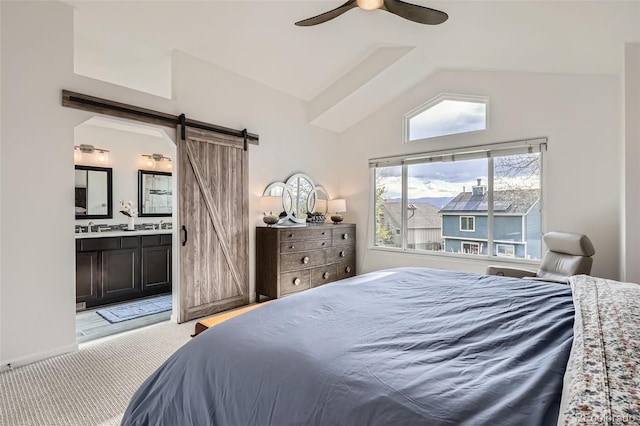 bedroom featuring a sink, light carpet, a barn door, ensuite bath, and vaulted ceiling